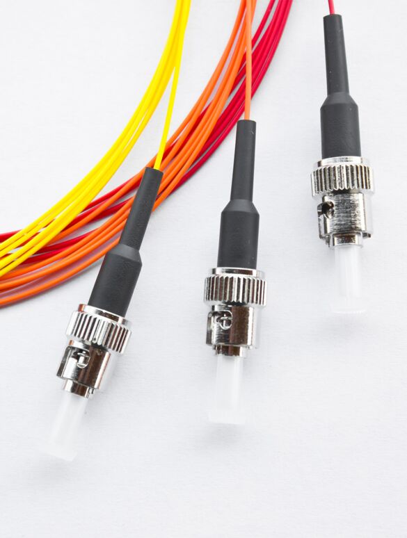 Drei vorkonfektionierte LWL-Patchkabel in unterschiedlichen Farben nebeneinander